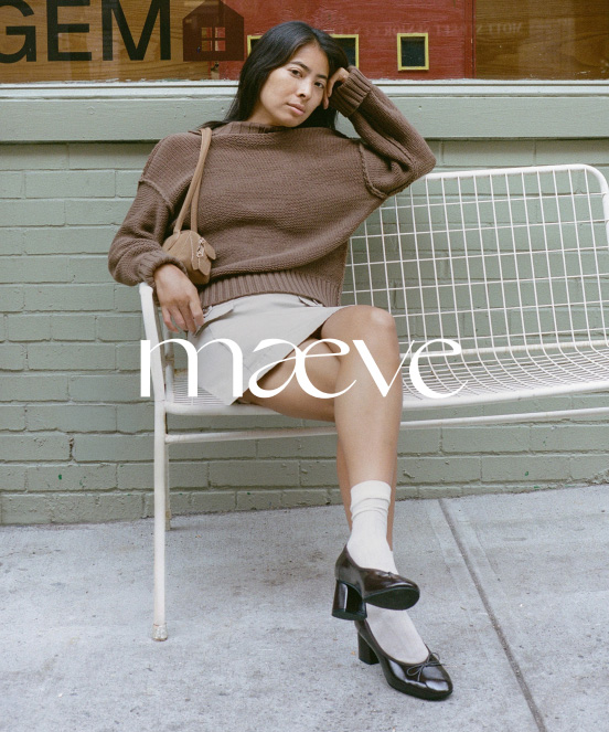 Woman in brown sweater and white shorts sitting on white metal bench against brick wall with maeve text overlay