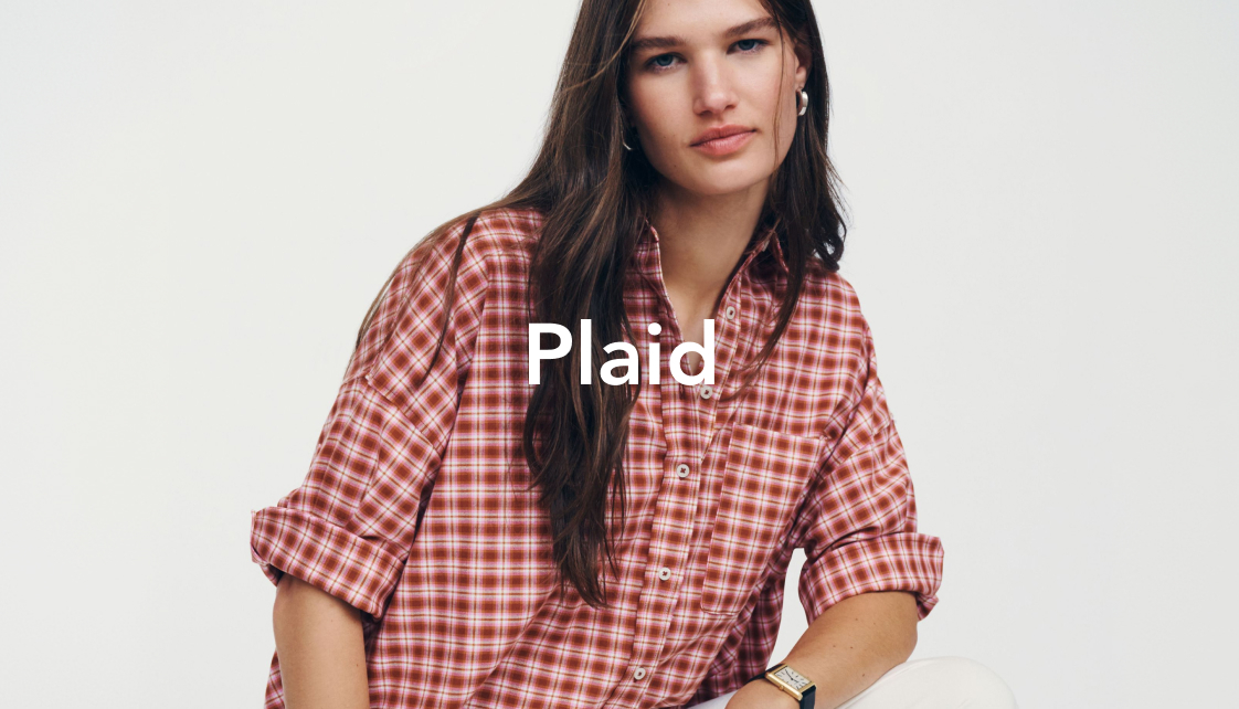 Woman wearing red and white plaid button-up shirt with rolled sleeves against light background