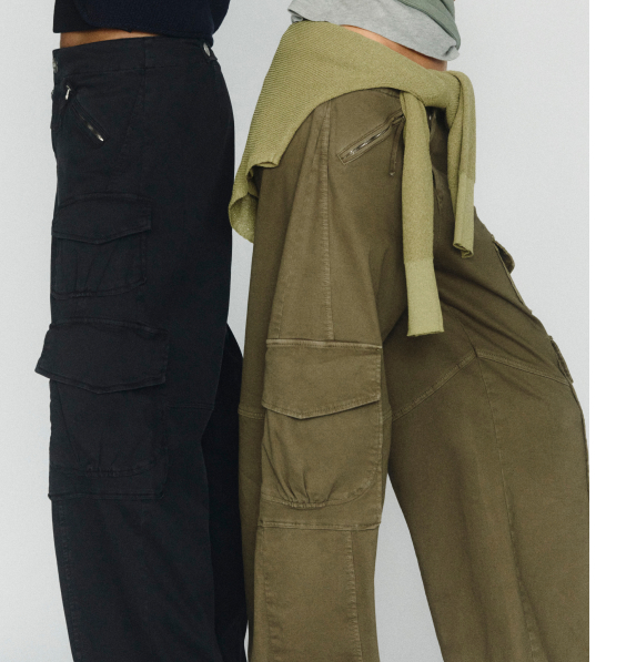 Two people wearing cargo pants, one in black and one in olive green, with a yellow sweater tied around the waist.