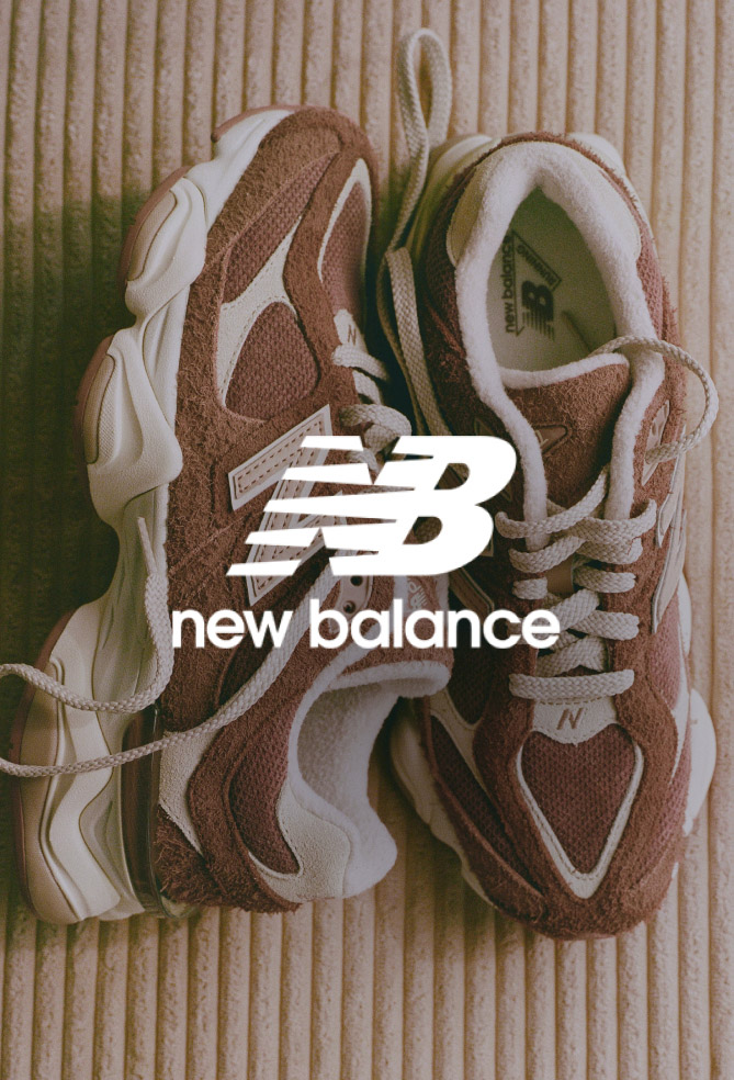 Pair of brown and white New Balance sneakers on textured beige surface with New Balance logo overlay in white.