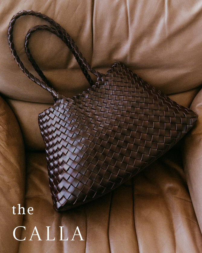 Brown woven leather handbag with braided handles on tan leather couch with text the CALLA in white letters