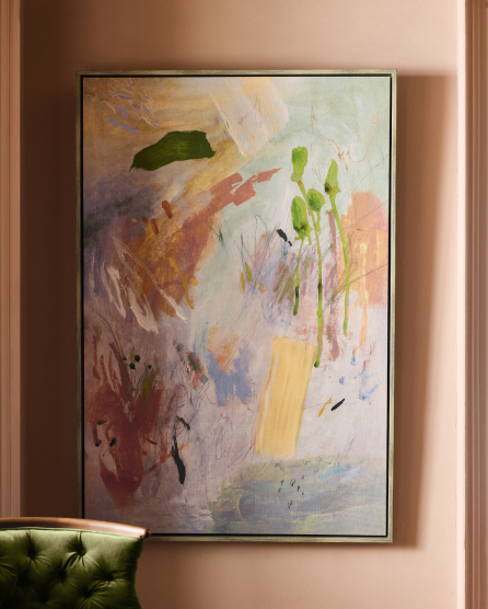 Abstract painting with colorful brushstrokes in green, pink, purple, yellow, and orange tones, framed in black on a pink wall.