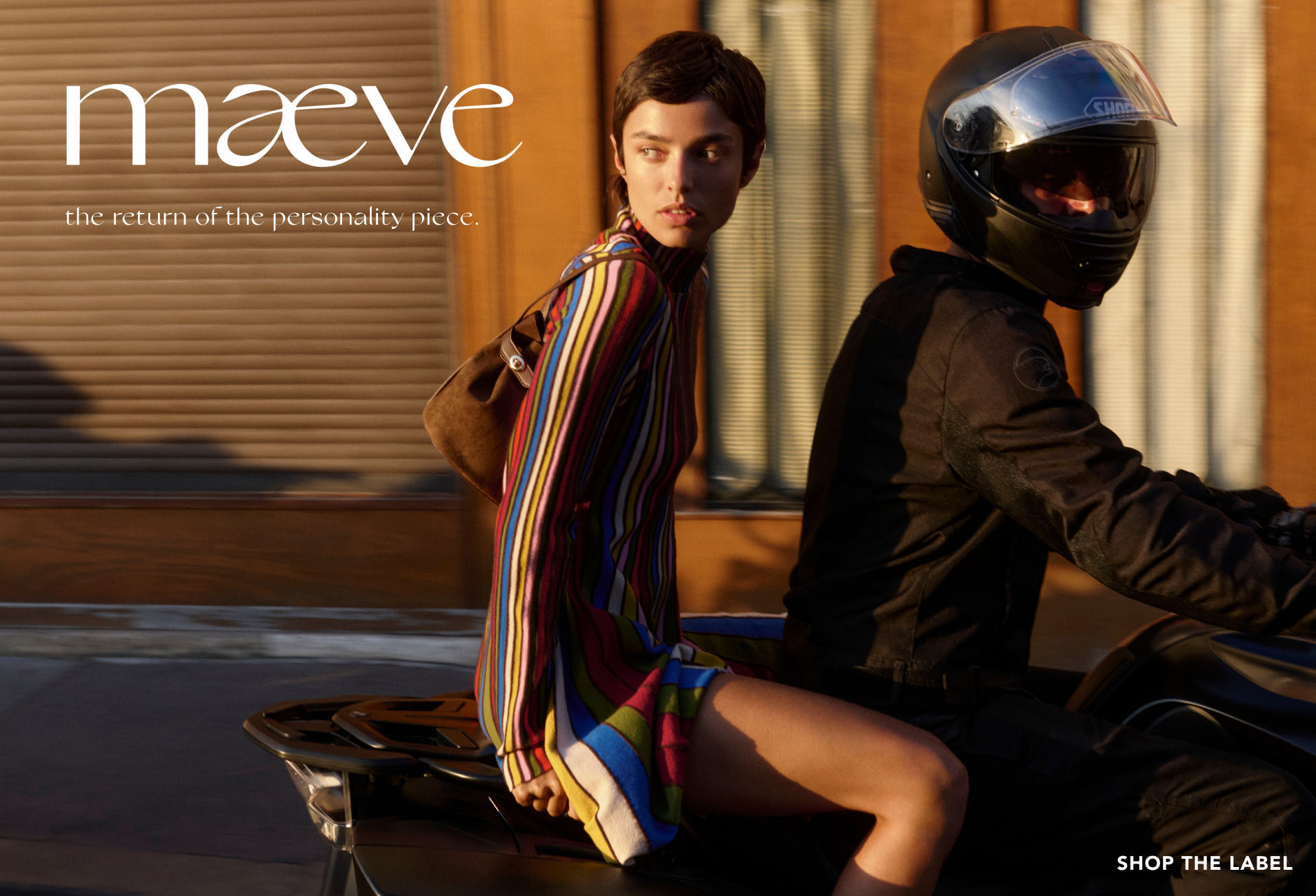 Woman in colorful striped top on motorcycle with helmeted rider. Text reads maeve the return of the personality piece.