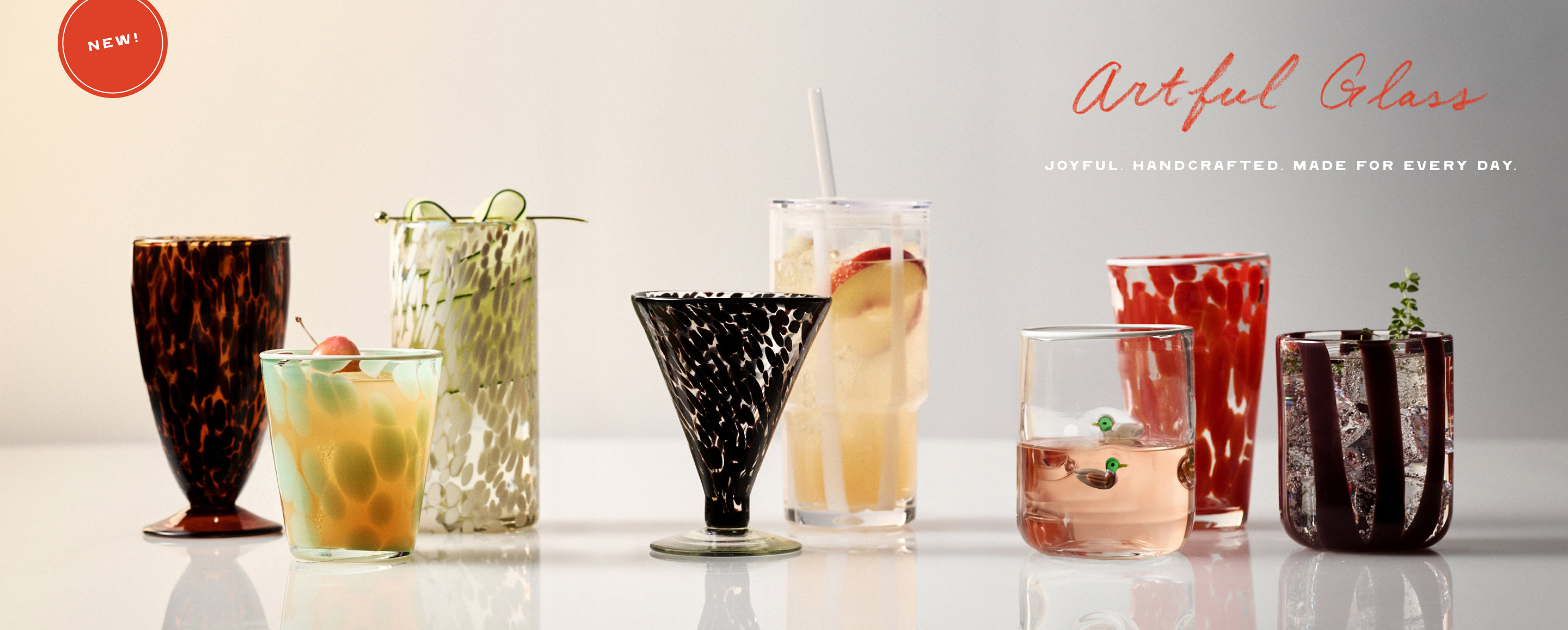Artful Glass collection of handcrafted drinkware in various colors and patterns with NEW badge and tagline Joyful. Handcrafted.