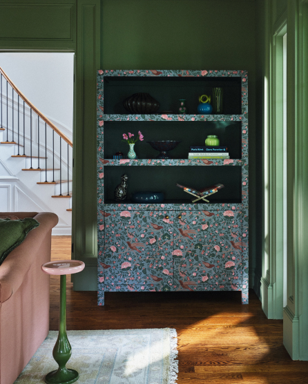 Built-in shelving unit with colorful terrazzo-style frame and dark green interior, displaying decorative objects in a green-walled alcove.