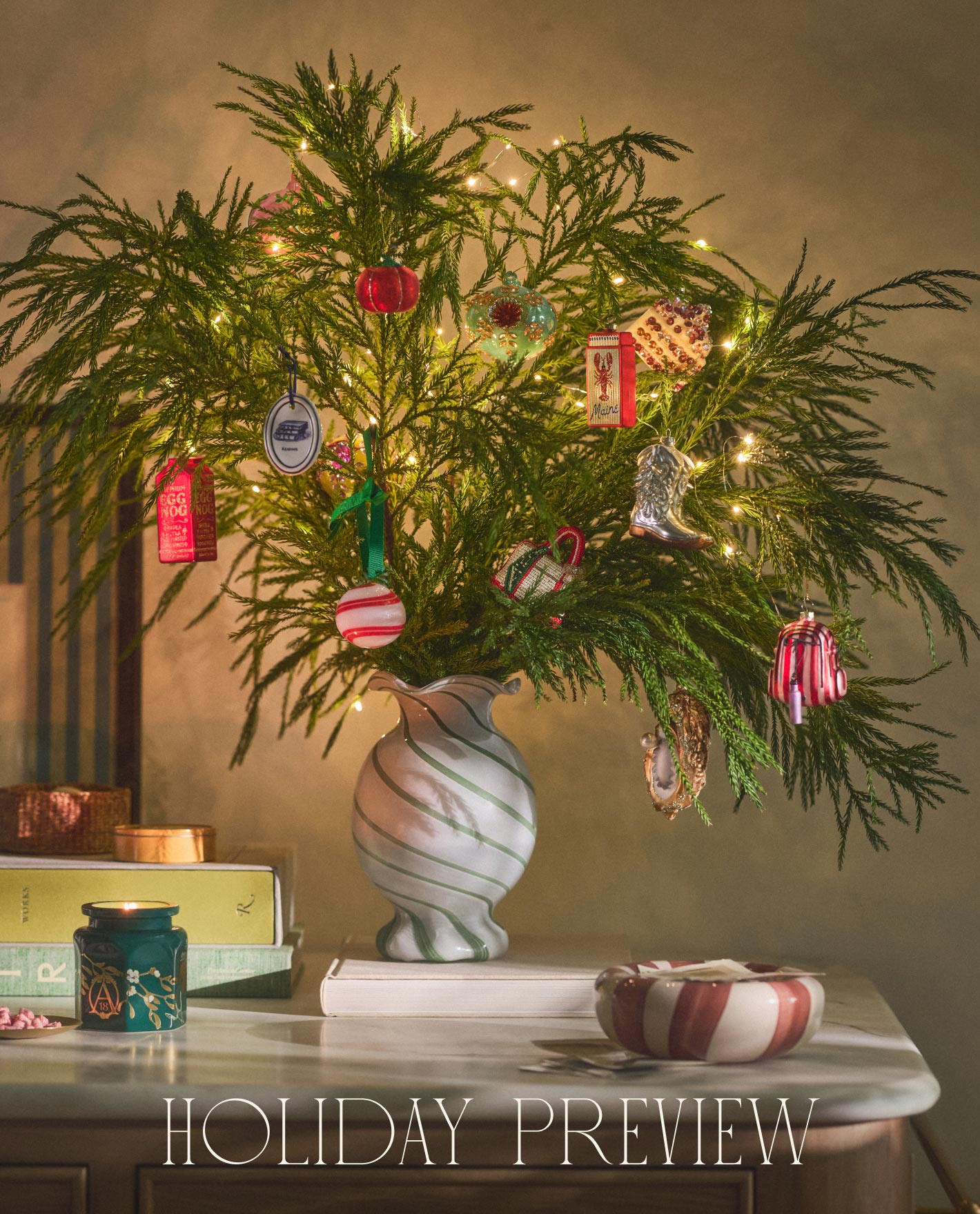 Evergreen branches in a white swirl vase decorated with colorful ornaments and string lights with text "HOLIDAY PREVIEW"