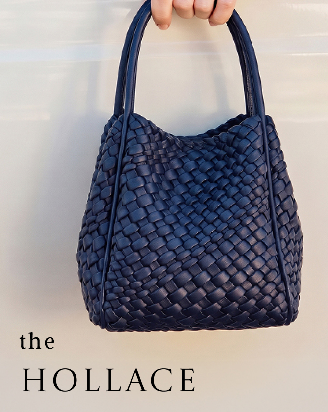 Hand holding a navy blue woven leather handbag with text "the HOLLACE" on light background