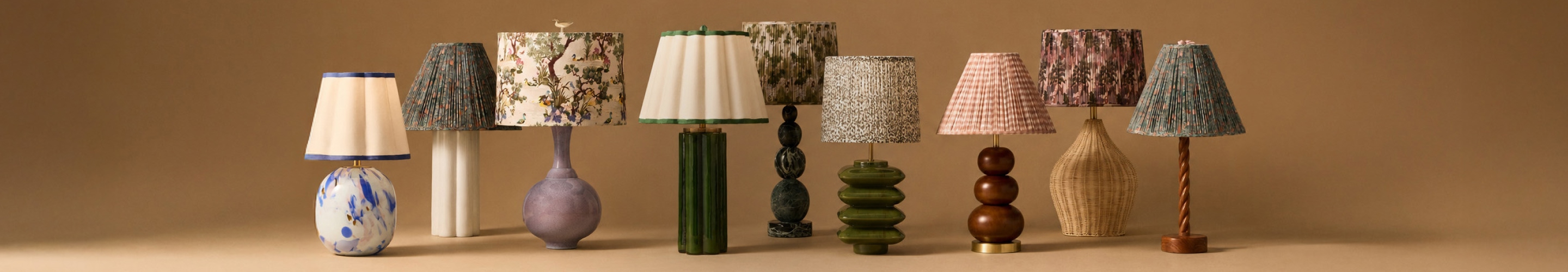 Collection of decorative table lamps with various patterned shades and bases in different shapes and colors against a tan background.