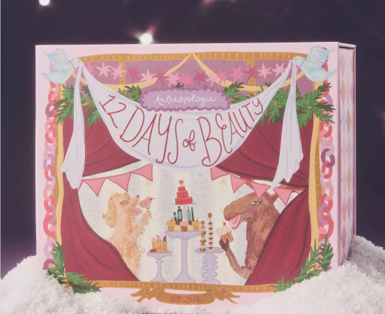 Open book displaying illustrated cover with "12 Days of Beauty" text, red curtains, unicorns, and festive decorations on white snow.