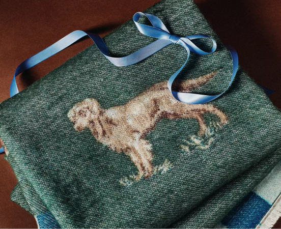 Green woven tote bag with embroidered golden retriever design, tied with blue ribbon bow on wooden surface.