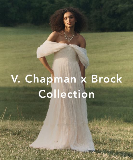 Woman in white off-shoulder gown with statement necklace standing in grassy field. Text reads V. Chapman x Brock Collection.
