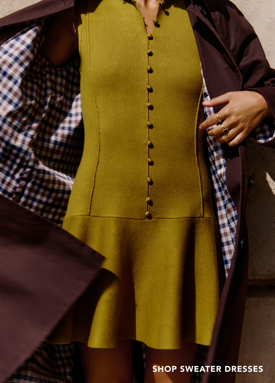 Woman wearing mustard yellow button-front sweater dress with brown blazer over plaid shirt. Text reads "SHOP SWEATER DRESSES"