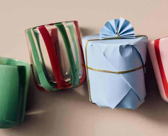 Four decorative mugs with colorful patterns including dogs, hearts, and geometric designs, arranged in a light blue gift box.
