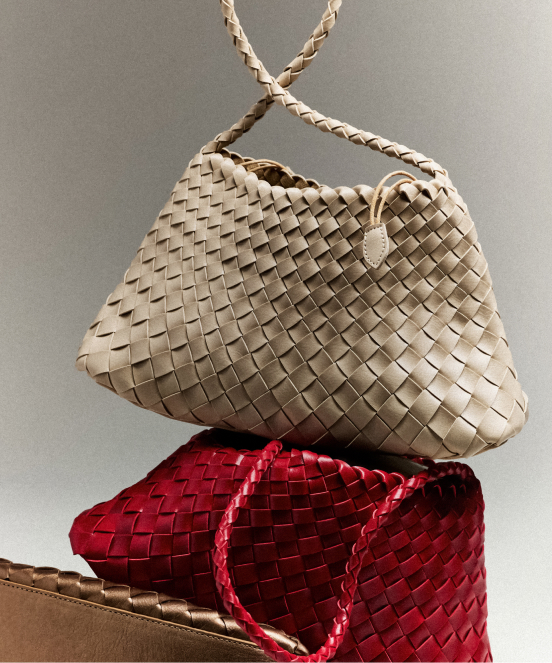 Beige woven leather handbag with braided strap stacked on top of a red woven leather bag against a neutral background.