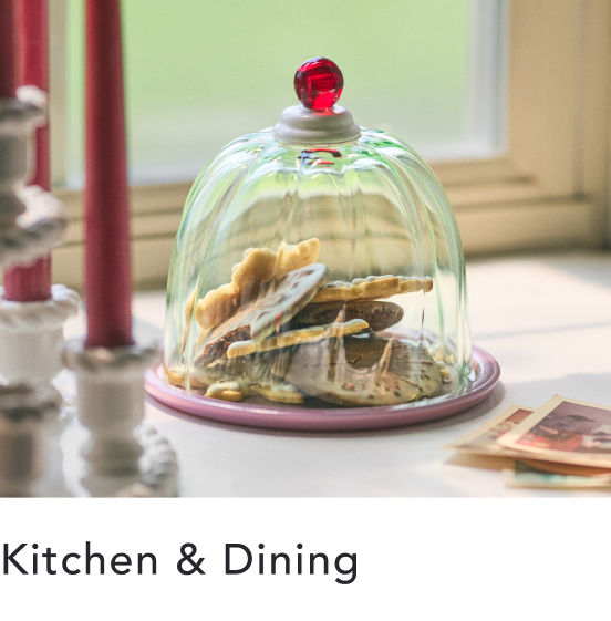 Glass dome with red knob on pink plate displaying stacked cookies, with text "Kitchen & Dining" below