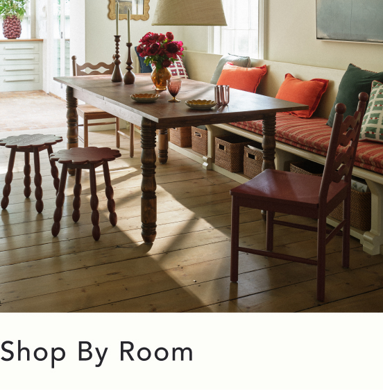 Bright dining area with wooden table, turned-leg stools, built-in bench with orange cushions, and text "Shop By Room"