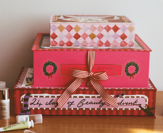 Stack of three decorative holiday boxes with diamond patterns and wreaths, tied with striped ribbon, labeled beauty advent.