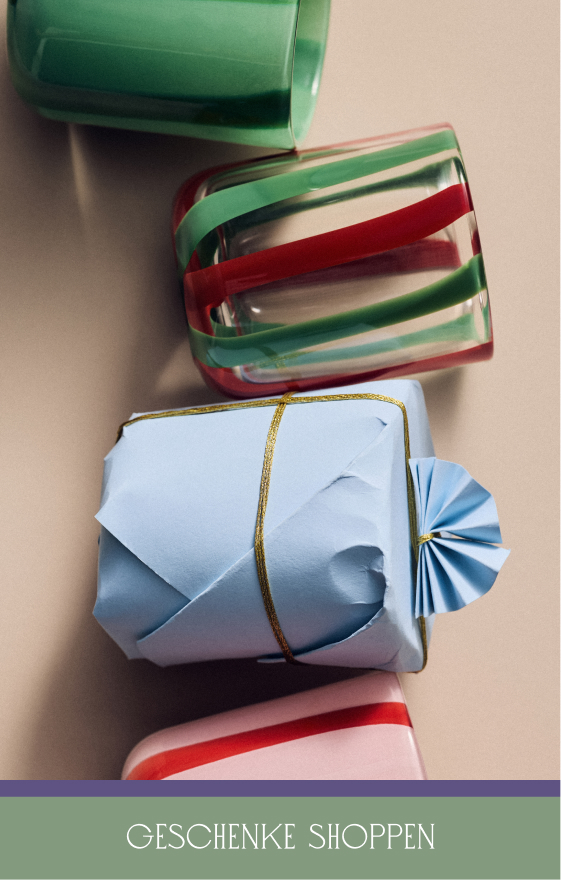 Wrapped gifts in green, red, white striped paper and blue paper with gold ribbon and bow, with text "SHOP GIFTS" below