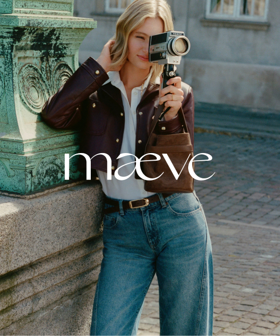 Woman with blonde hair holding vintage camera, wearing brown jacket, white shirt, and jeans. Text reads "maeve"