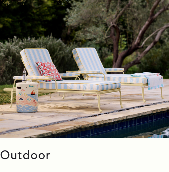 Two yellow and white striped lounge chairs beside a pool with a decorative cooler and red patterned towel in a garden setting.