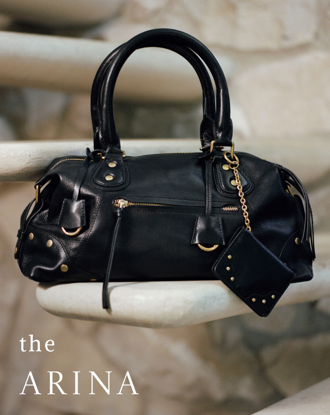 Black leather handbag with gold hardware and chain detail displayed on white surface with text "the ARINA" in lower left corner.