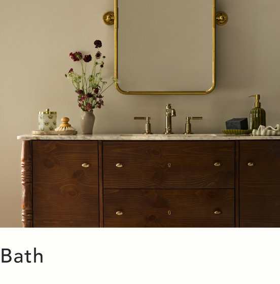 Elegant bathroom vanity with dark wood drawers, white marble top, brass faucet, gold-framed mirror, and purple flowers