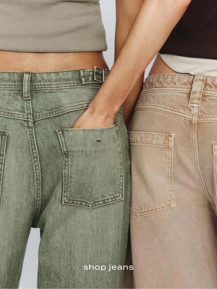 Two people standing side by side wearing olive green and beige jeans with visible back pockets. Text reads "shop jeans"