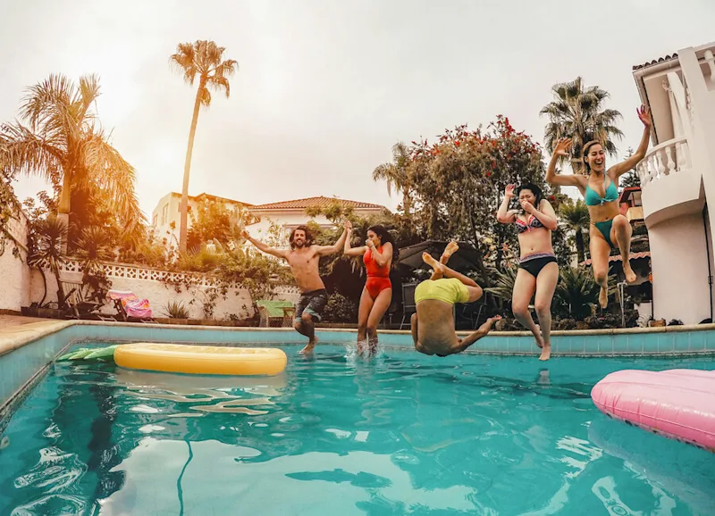 Group of friends jumping into the swimming pool on holiday in Croatia