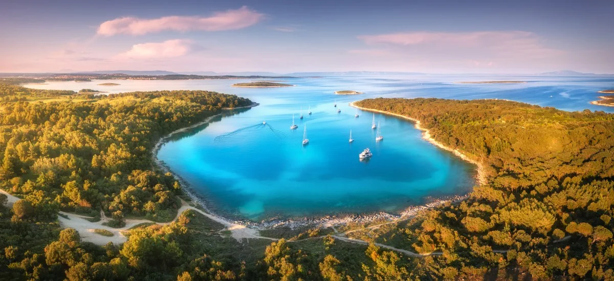 Luftfoto af en bugt med sejlbåde og turkisblåt vand i Istrien, Kroatien.