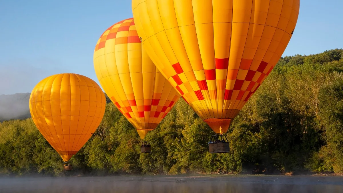 hot air balloons fly low over dordogne river in southern france