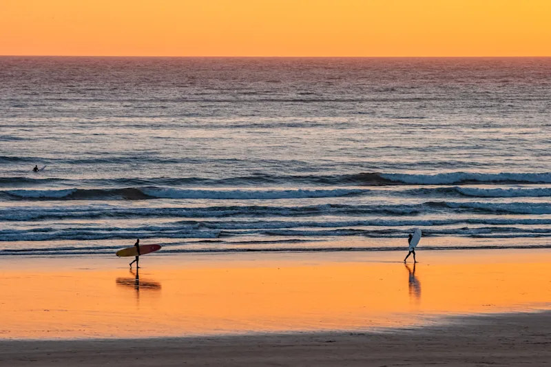 Surfers at sunset on Croyde Bay Beach, North Devon, UK