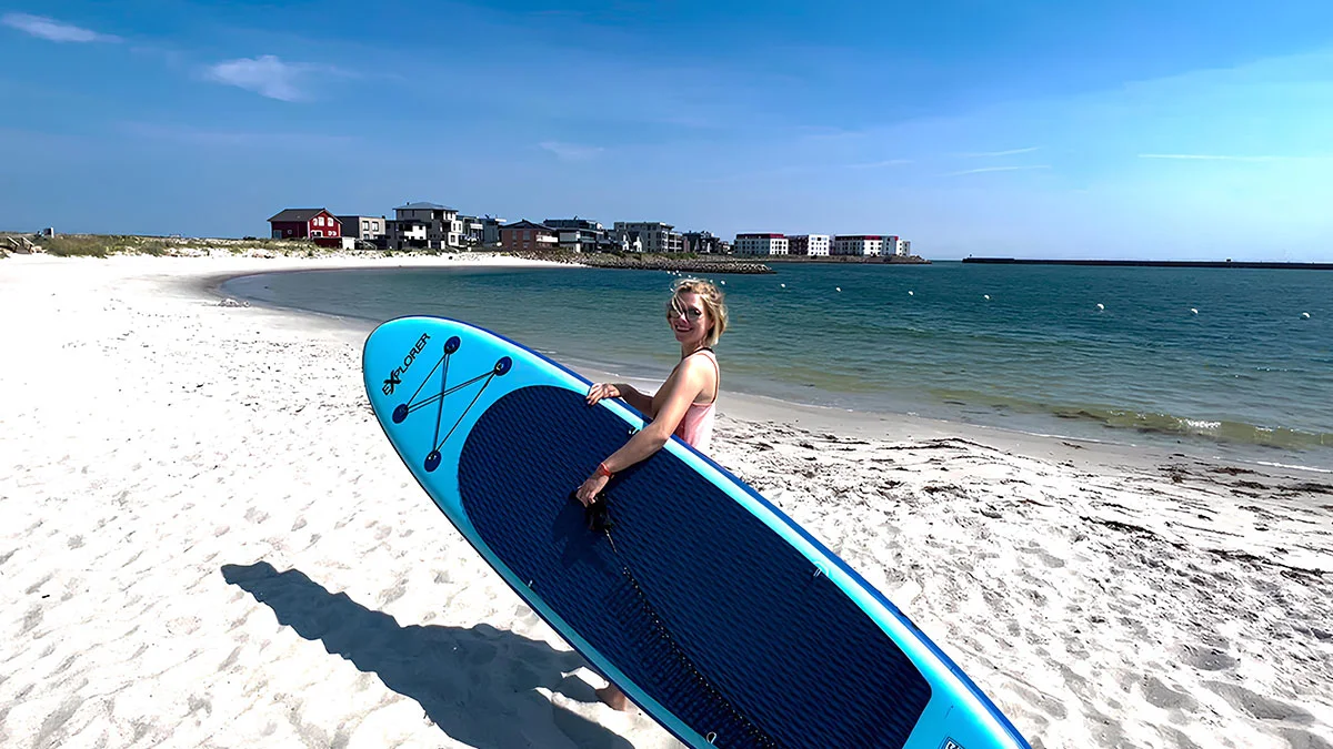 Frau mit Stand-Up-Paddle Board am Strand im OstseeResort Olpenitz.