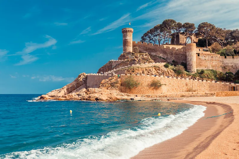 Udsigt over stranden og slottet i Tossa de Mar, Catalonien, med bølger og solskin, tæt på Barcelona