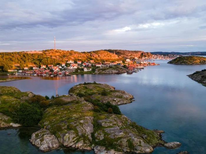 Dronebillede af Fjällbacka i Bohuslän, hvor morgenlyset kaster en blød glød over byen og skærgården