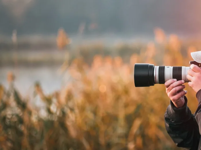 Professional wildlife photographer man taking pictures with digital camera equipment of birds and animals in nature.