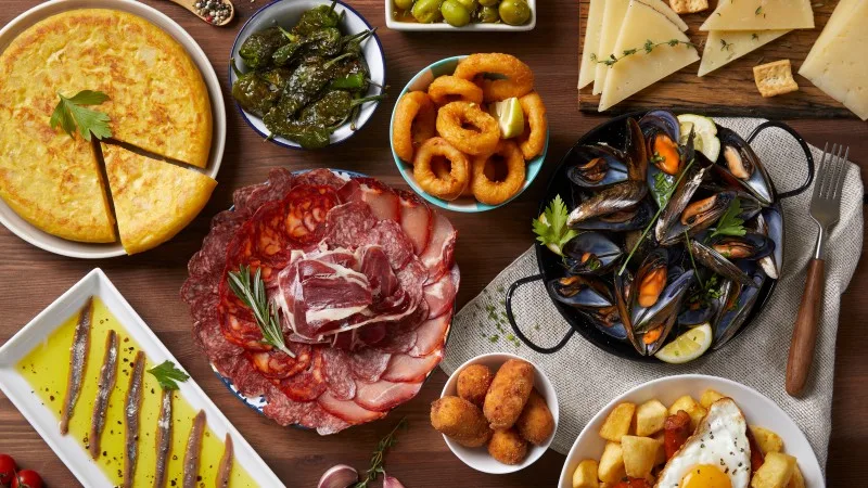 A wooden table with typical Spanish food seen from above