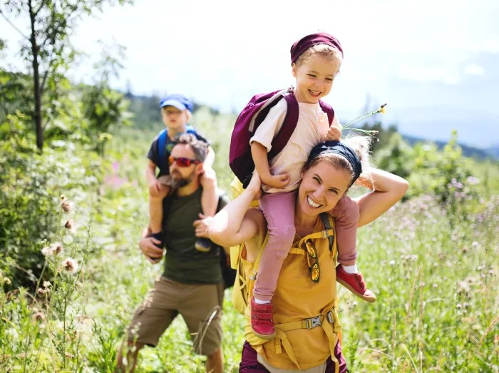 Family with small children hiking outdoors in summer nature.