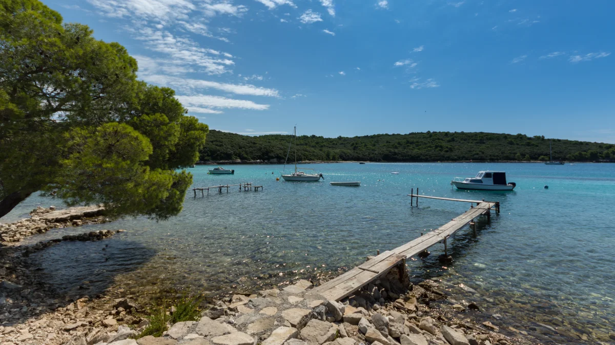 Beach in Banjole, Croatia, with a jetty leading into the turquoise water.