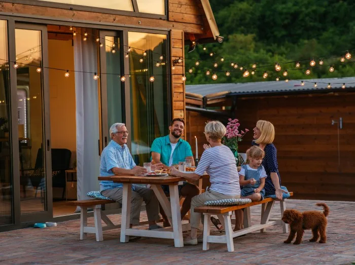 A family with their dog enjoying dinner outside during a stay in a holiday home