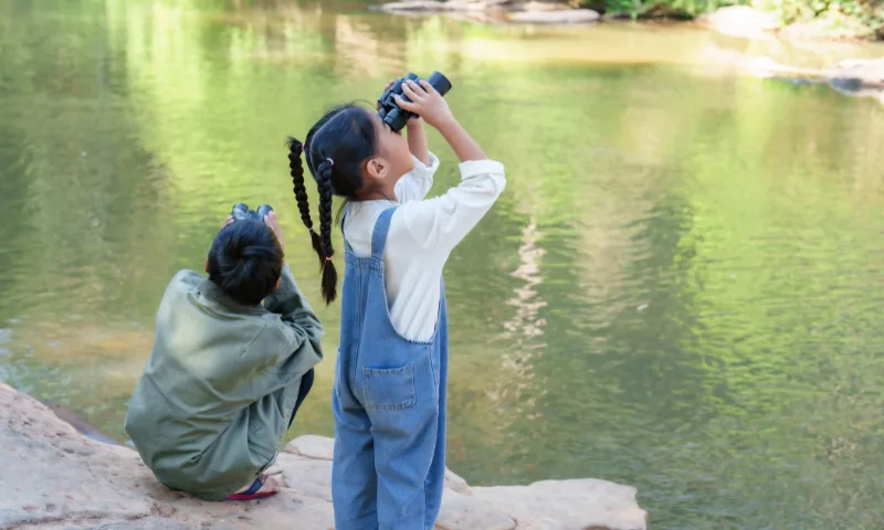 Children with binoculars by the water