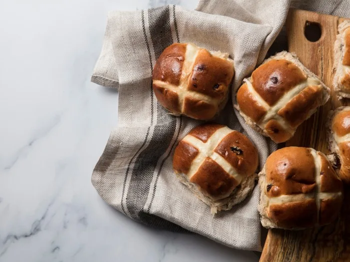 Traditional hot cross buns with raisins on a wooden board