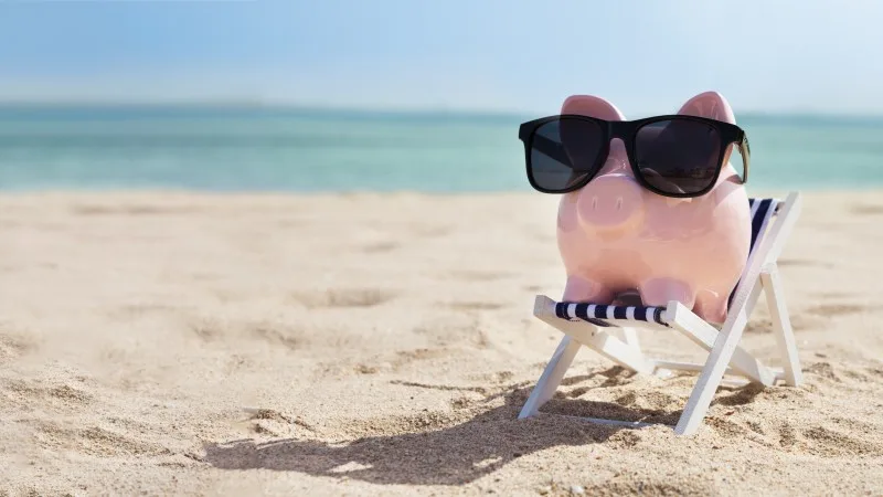 Pink Piggybank On Deck Chair Over The Sandy Beach
