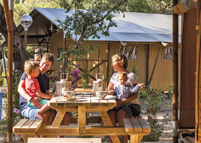 Family having a picnic outside a safari tent at Maesmawr Farm Resort (MAEF) in Caersws, Nr Newtown, Mid Wales, UK