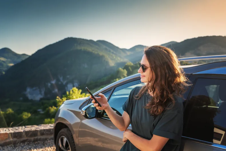Eine Frau macht eine Pause am Auto während eines Roadtrips.