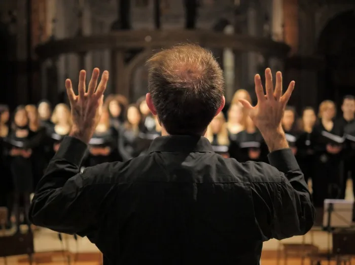 Musician leads a choir during a concert in a cathedral.