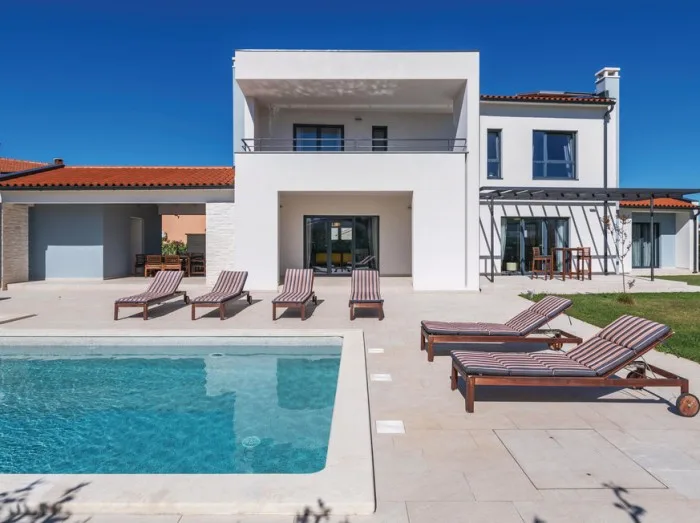 Blick auf einen Pool mit Sonnenliegen in einem Luxusferienhaus in Fazana, Kroatien.