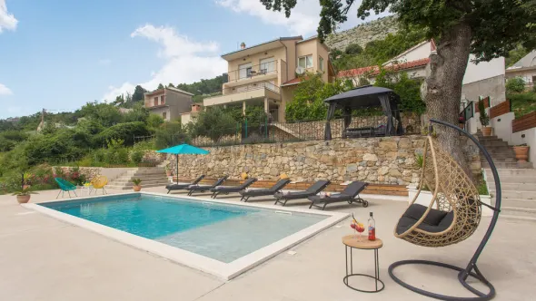 Pool mit Sonnenliegen vor einem Ferienhaus in Split, Kroatien.