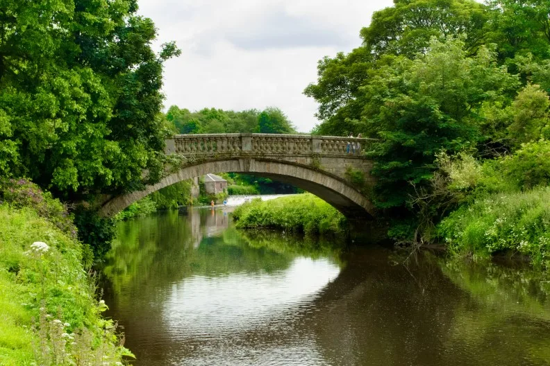 Stone bridge over the White Cart Water river in Pollok Country Park, Glasgow city centre, Scotland