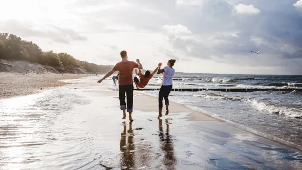 Eine Familie geht am Strand spazieren.