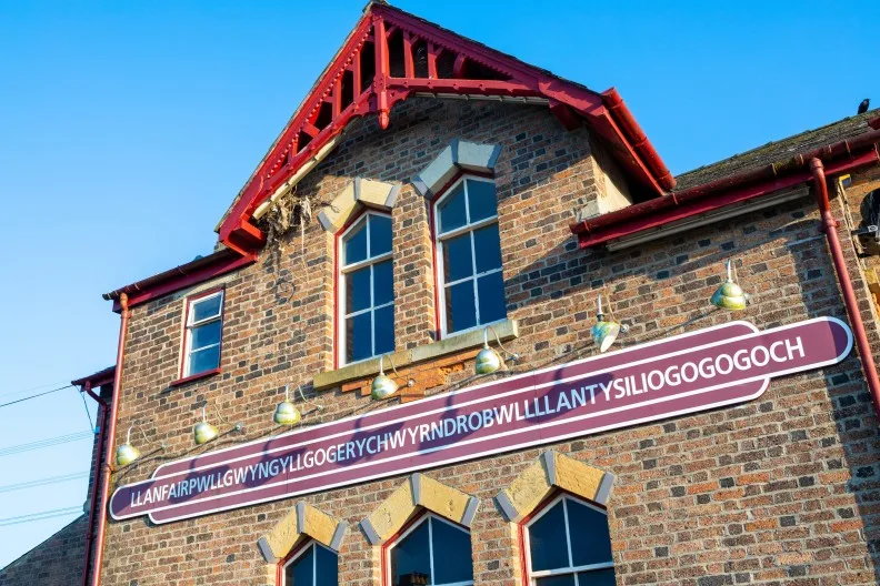 Train station showing village name of Llanfairpwllgwyngyllgogerychwyrndrobwllllantysiliogogogoch, Wales, UK